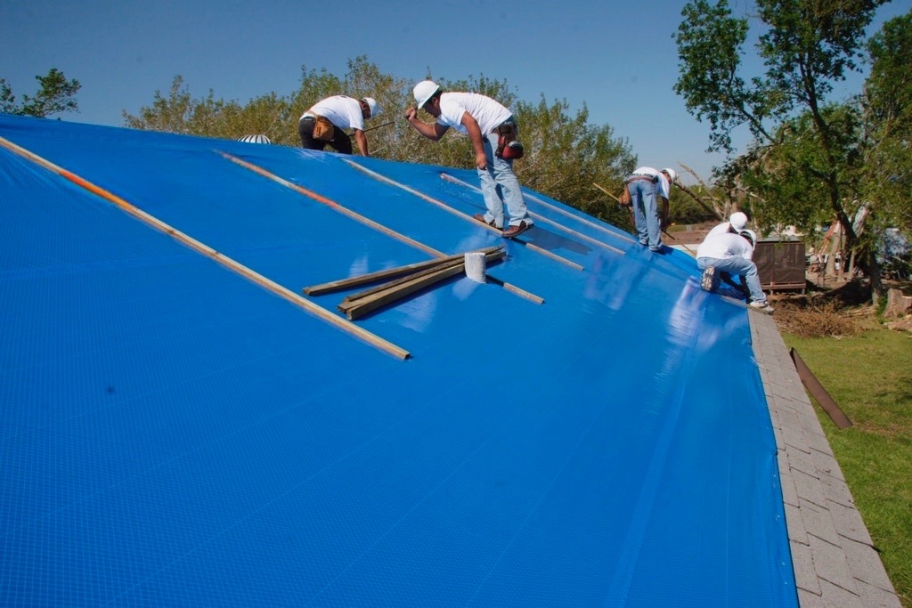 workers tarping a roof